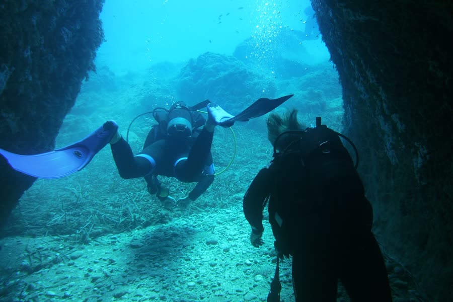 Zwei Taucher schwimmen durch eine Felsgasse